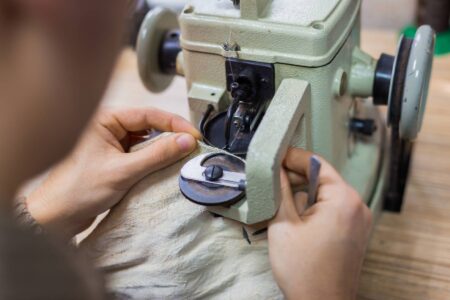 Skinner using furrier machine for stitching fur skin at atelier
